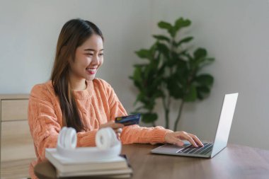 Bilgisayardan eve internet üzerinden alışveriş yapmak için kredi kartı numarasına giren kadınlar.