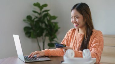 Bilgisayardan eve internet üzerinden alışveriş yapmak için kredi kartı numarasına giren kadınlar.