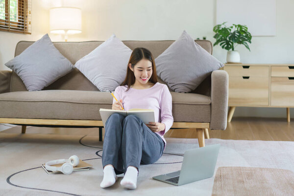 Женщины читают бизнес-данные на ноутбуке и пишут заметки, сидя дома на полу в стиле жизни.