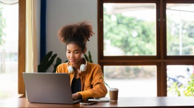 Afrikalı Amerikalı iş kadını yeni iş planlama ve kafede dizüstü bilgisayar kullanmayı düşünüyor..