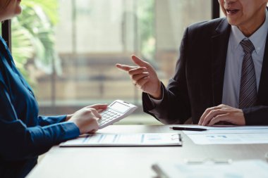 İş arkadaşları yeni iş dünyasının pazarlanması konusunda hesap makinesi ve beyin fırtınası kullanarak birlikte çalışıyorlar.