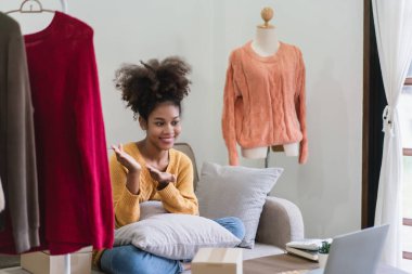 Afrikalı Amerikalı moda tüccarı kadın canlı yayında online kıyafetlerini sunuyor ve satıyor..