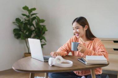 Kadınlar kahve içmek için yerde oturuyor ve evdeki yaşam tarzlarıyla bilgisayarlarına finansal veriler yazıyorlar..