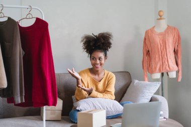 Afrikalı Amerikalı moda tüccarı kadın canlı yayında online kıyafetlerini sunuyor ve satıyor..