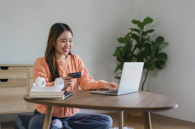 Bilgisayardan eve internet üzerinden alışveriş yapmak için kredi kartı numarasına giren kadınlar.