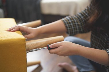 Kadınlar sandalyenin bacağını monte etmek ve mobilya yapmak için tornavida teçhizatıyla vidayı sıkarlar..