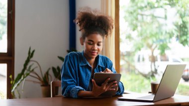 Afrikalı Amerikalı iş kadını yeni iş planlama ve tablet üzerine notlar yazma hakkında düşünüyor..