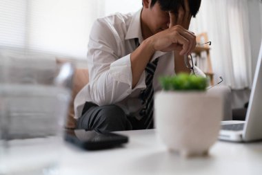 İş adamı çok çalıştığı için yorgun ve stresliyken gözlüğünü ve yüzünü elleriyle kapatır..