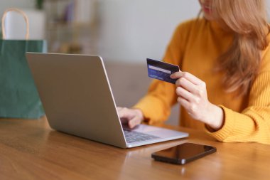 Ev konsepti ile ilgili çalışmalar, İş kadını dizüstü bilgisayarına kredi kartı verileri yazarak online alışveriş yapıyor.