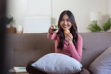 Kadınlar ekmek yerken ve uzaktan kumandayla kanal seçerken evde yaşam tarzında televizyon izliyorlar..