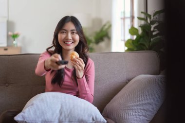 Kadınlar ekmek yerken ve uzaktan kumandayla kanal seçerken evde yaşam tarzında televizyon izliyorlar..