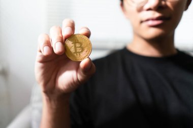 Altın kripto para tutan genç adam bitcoin gelecekteki yaşam tarzı için sanal elektronik para ile.