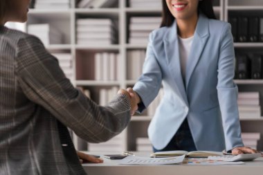 İki iş kadını yeni iş projesini tartışırken el sıkışıyor ve selamlaşıyor..