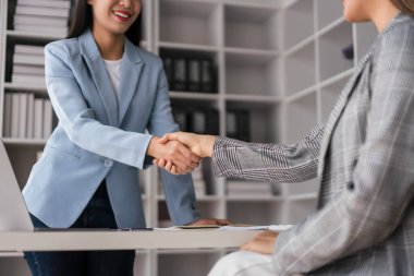 İki iş kadını yeni iş projesini tartışırken el sıkışıyor ve selamlaşıyor..