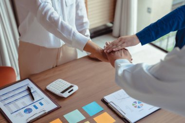 Bir grup iş arkadaşı yeni iş konularını tartışırken ve birlikte çalışırken el ele tutuşuyorlar..