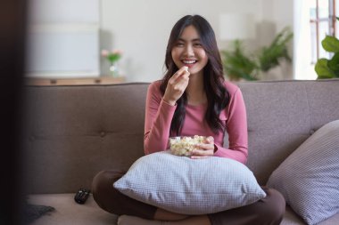 Kadınlar kanepede oturup patlamış mısır yiyor ve TV 'de film seyrediyor..