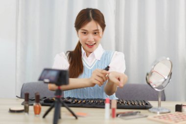 Beauty blogger concept, Young Asian woman doing test concealer on hand and review in live streaming.