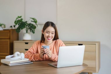 Yerde oturup kahve içen ve dizüstü bilgisayardan film izleyen kadınlar..