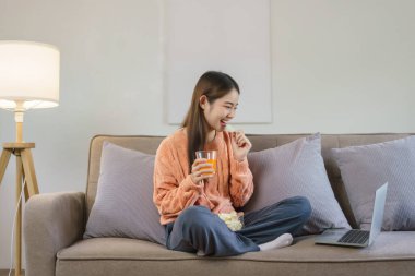 Kadınlar evde dizüstü bilgisayarda film izlerken portakal suyu içip abur cubur yiyor..