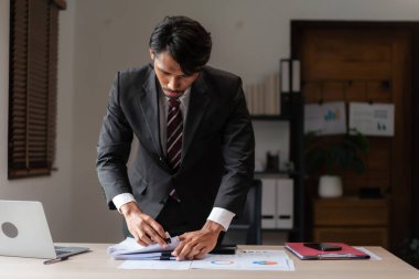 Girişim projesinin pazarlama verilerini inceledikten sonra iş belgesini istifleyen işadamı.