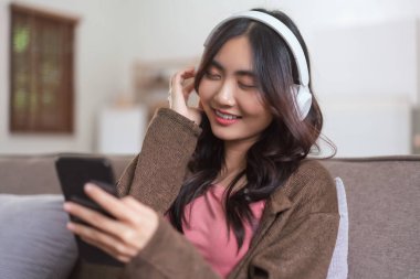 Kulaklık takan ve akıllı telefondan müzik dinleyen kadınlar evde yaşam tarzıyla eğleniyorlar..