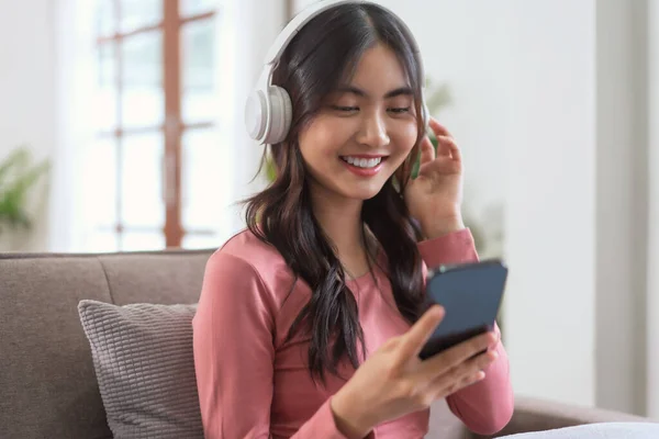 Perempuan Mengenakan Headphone Untuk Mendengarkan Musik Telepon Pintar Sementara Waktu Stok Foto Bebas Royalti