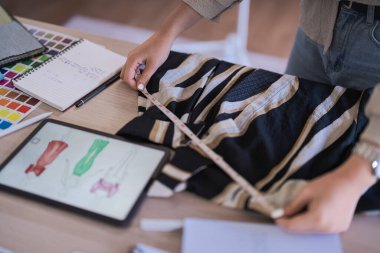 Moda tasarımcısı kadınlar boyutu ölçmek ve ayrıntıları kontrol etmek için ölçü bandı kullanırlar.