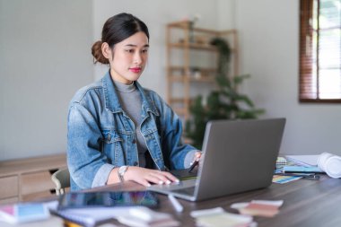 Dizüstü bilgisayarda yazan ve grafik tasarımı için dijital tablet üzerinde çalışan grafik tasarımcı kadınlar.