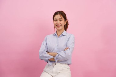 Kadınlar otururken gülümsüyor ve kollarını kapalı pembe arka planda boş bir alanla kavuşturuyorlar..