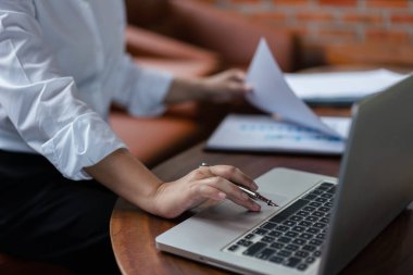 Finans belgesini kontrol eden ve klavyede veri yazmaya çalışan iş kadınının elleri.