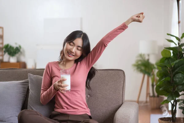 Women sit on sofa to stretching and drinking milk after wake up in morning with lifestyle at home.