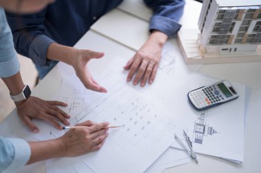 İki mühendis iç mimari yapılar hakkındaki çizimleri incelemek ve planlar hakkında veri yazmak için tartışırken, aynı zamanda inşaat planının analizini işyerinde birlikte yapmak için teknik konular üzerinde tartışıyorlar..