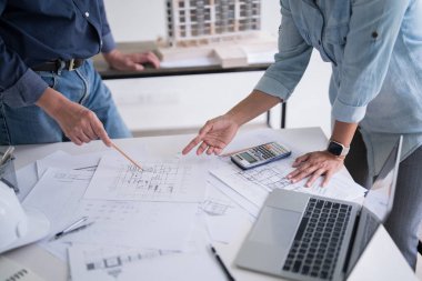 İki mühendis, inşaat planı ve inşa modelinin teknik olarak tartışılacağı iç mimari binanın planına işaret ederek, iş yerinde birlikte çalışacaklar..
