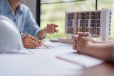 Mimar kadın, inşaat planıyla birlikte inşaat projesini meslektaşına anlatıyor..