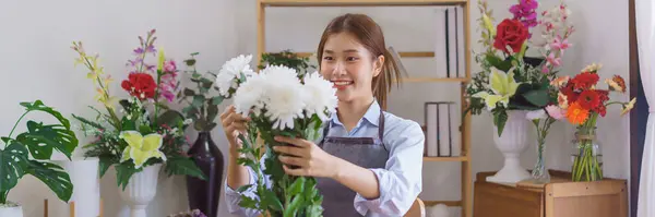 Florist concept, Woman florist selecting white chrysanthemum to making bouquet in flower shop.