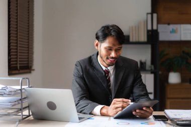 Girişim projesinin stratejisini analiz ederken, iş adamı tablet üzerine iş verileri yazıyor.