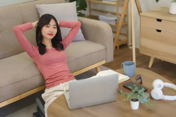 Young businesswoman sits on floor to relaxation with watching movie on laptop after working at home.