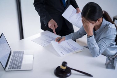 İş adamı avukata finans verilerini açıklarken, kadın avukat da iş belgesini okuyor ve hukuk firmasındaki yasal anlaşma ve iş sözleşmesinin şartları hakkında analize vurgulanıyor..