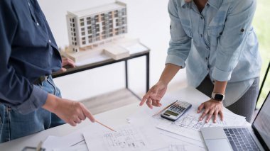 İki mühendis, inşaat planı ve inşa modelinin teknik olarak tartışılacağı iç mimari binanın planına işaret ederek, iş yerinde birlikte çalışacaklar..