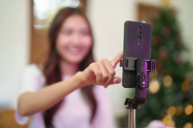 Genç Asyalı Vj kadınları akıllı telefon kullanıyor ve sabah konuşmalarına video kaydetmeye hazırlanıyor. Ev stüdyosundaki oturma odasında mutlulukla çalışırken canlı yayında haberlerden bahsediyor..