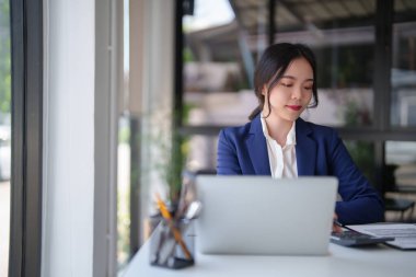 İstatistikleri hesaplamak ve belge üzerindeki mali verileri kontrol etmek için hesap makinesi kullanan iş kadınları, iş yerindeki yeni başlangıç projesi hakkında strateji yatırımı ve yönetimini analiz etmeye çalışırken,.