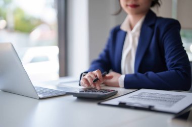 İş kadınları, dijital dizüstü bilgisayarda belge ve finans verilerini hesap makinesiyle kontrol ederken, aynı zamanda iş yerindeki yeni başlangıç projesiyle ilgili strateji yatırımları ve yönetimi analiz etmeye çalışıyorlar..