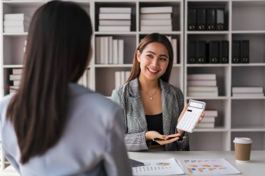 Businesswoman showing numbers of business profit to partner and discuss about new project together.