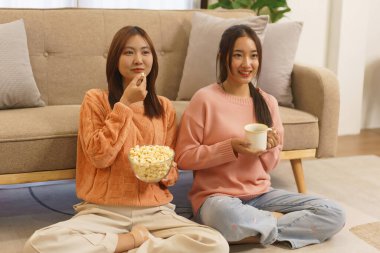 Ev konseptinde yaşam tarzı, LGBT lezbiyen çifti patlamış mısır yiyor ve film izlerken kahve içiyor.