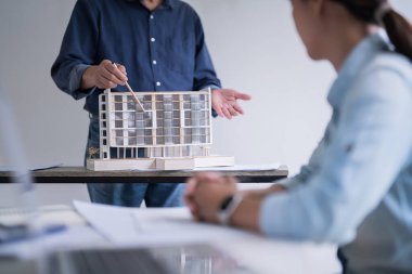 İnşaat modelini işaret eden erkek mühendis, iç mimari yapı ve inşaat planını iş yerinde birlikte analiz yaparken meslektaşına anlatıyor..