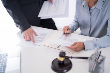İş adamı belgeye işaret ediyor ve iş hakkındaki mali verileri avukata açıklarken, kadın avukat da hukuk firmasındaki yasal anlaşma ve iş sözleşmesinin şartları hakkında danışmanlık yapıyor..