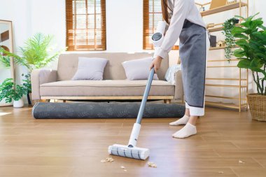 Temizlik konsepti. Hizmetçi oturma odasındaki tozları paspaslamak ve temizlemek için paspas kullanıyor..