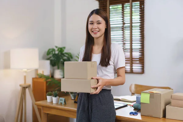 Online selling concept, Asian business women holds parcel boxes of product for delivery to customer.