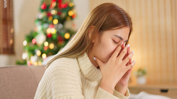 Winter season concept, Women stressed and exhausted while resting on couch near christmas tree.
