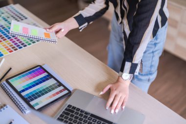 Grafik tasarımcı kadınlar grafik tasarımı hakkında çalışmak için dizüstü ve seçim rengi üzerinde veri okuyorlar.